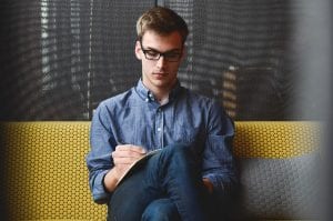 Gentleman seated on a couch, writing Gentleman seated on a couch, writing