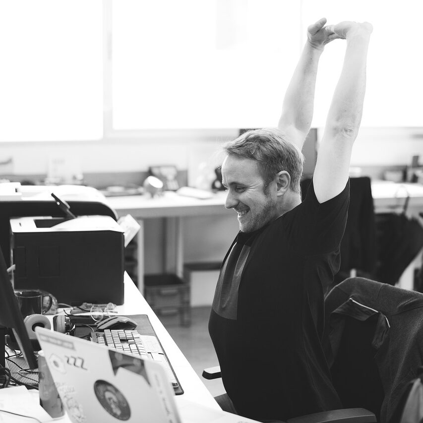 Black-and-White-Male-Worker-Stretching-at-Computer-Desk-1200-px
